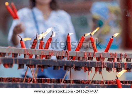 Picture of lighting a red candle placed on a stand specifically for candles that are heated by the flame and candle tears. It's another item of worship for sacred things according to personal beliefs.