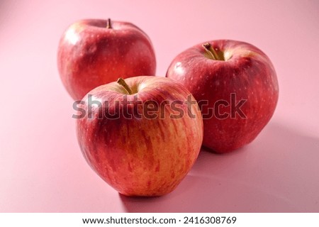 three red apples on a pink background