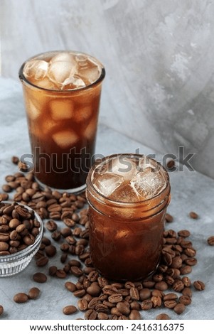 Two Glass of Homemade Iced Americano Coffee with Beans on Cement Grey Background  Royalty-Free Stock Photo #2416316375