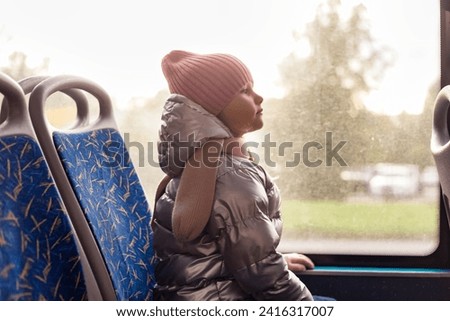 Side view of child girl 5 year old riders on public bus metropolitan transport, looking ahead. Cute little kid girl in trolleybus, city lifestyle. Public urban transport concept. Copy ad text space Royalty-Free Stock Photo #2416317007