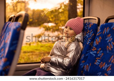 Adorable kid girl riders on public bus metropolitan transport, smile looking away. Cute child girl 5 year old travels in trolleybus, city lifestyle. Public urban transport concept. Copy ad text space Royalty-Free Stock Photo #2416317017