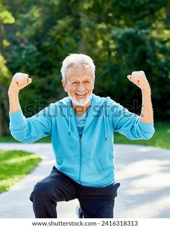 Smiling active senior man jogging exercising and having fun and celebrating success rasing hands taking a break in the park, concept of competition, winning, victory and strength Royalty-Free Stock Photo #2416318313