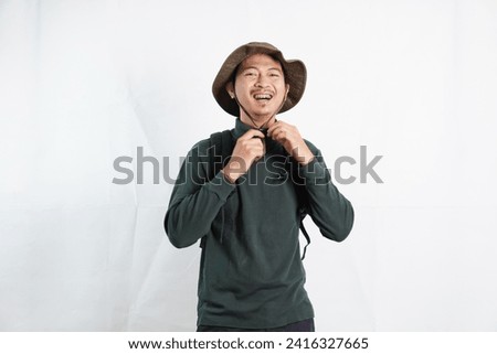 Young man wearing traveling hats and backpack standing over isolated white background very happy and excited doing smiling for success. Celebration