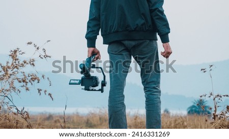 Nature photographer take photos with mirror camera on peak of mountain at morning sunrise. Filmmaker with Gimbal and professional video camera, Travel filmmaker or content creator concept. 