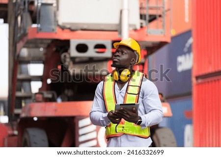 African American male container yard worker working and checking container boxes before loading at commercial dock site. Black male people worker inspecting container boxes from cargo freight ship