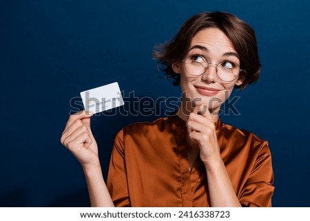 Photo of successful minded lady office banker look empty space hold bank card cashless nfc isolated on dark blue color background