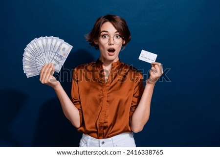 Photo portrait of attractive young woman shocked credit card money fan dressed stylish brown blouse isolated on dark brown color background