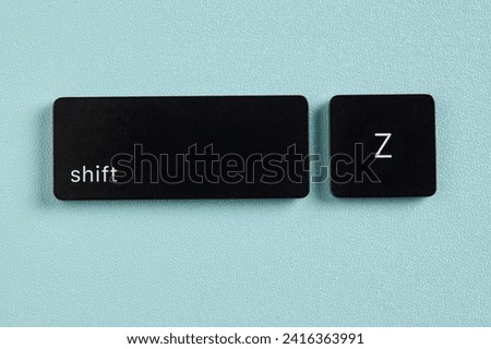 Shift key and Z key detached from keyboard on blue background Royalty-Free Stock Photo #2416363991