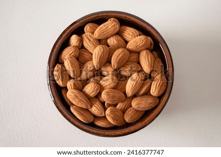Almonds in a baked clay plate seen from above on white background Royalty-Free Stock Photo #2416377747