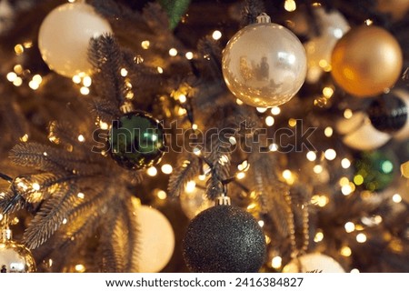 Close up of white, black, green and golden Christmas balls, garlands, string light handing on christmas tree with bokeh. Christmas decor, background with copy space. The concept of Christmas.