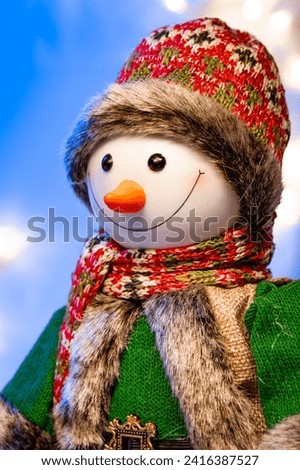 Snowman doll on a blue background close-up with stars and snow