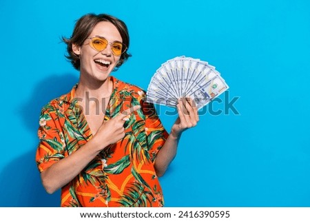 Photo of excited successful person toothy smile indicate finger hand hold dollar bills isolated on blue color background