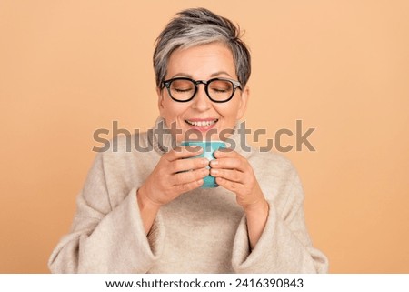 Portrait of positive grandmother closed eyes smell fresh aroma coffee mug isolated on beige color background