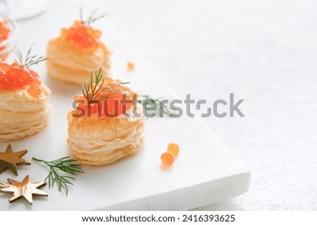 Salmon red caviar toast. Christmas canape or toast with red caviar on white plate on light background. Idea to xmas snack. Gourmet food. Texture of caviar. Seafood. 