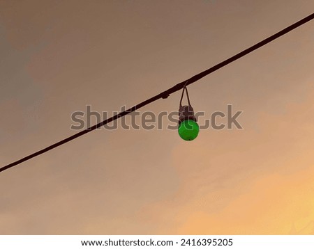 a photography of a traffic light hanging from a wire with a sky background.