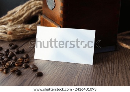 Empty business card mockup with coffee beans and vintage grinder on wooden table background. Mock up for branding identity. Blank template for your design.