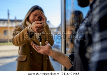 A worried customer delivers car keys to the mechanic at the workshop door, a moment reflecting concern and reliance on expert service.  Royalty-Free Stock Photo #2416401465