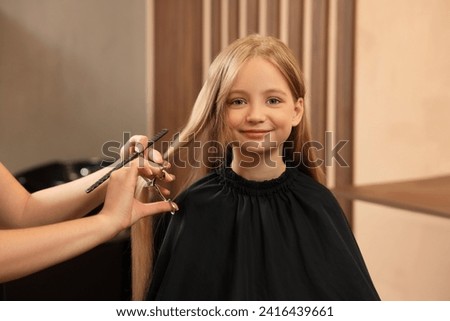 Professional hairdresser cutting girl's hair in beauty salon Royalty-Free Stock Photo #2416439661