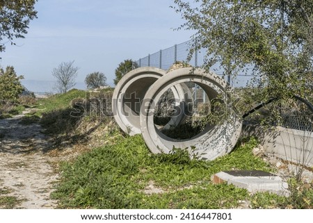 Large cement pipes abandoned in the middle of the field next to a fence