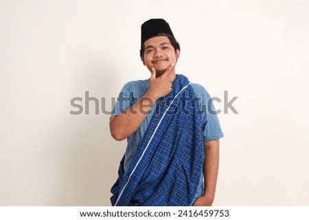 Confident young asian muslim boy with hat and scabbard standing posing and looking at the camera Royalty-Free Stock Photo #2416459753