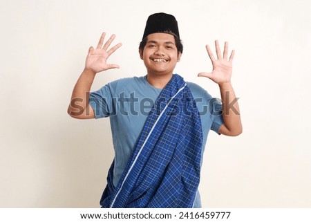 Happy young asian muslim boy standing while showing nine fingers. Isolated on white