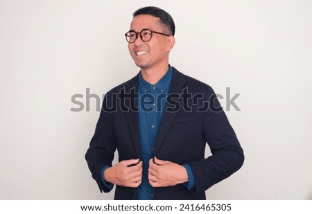 Asian businessman smiling and looking away confidently Royalty-Free Stock Photo #2416465305