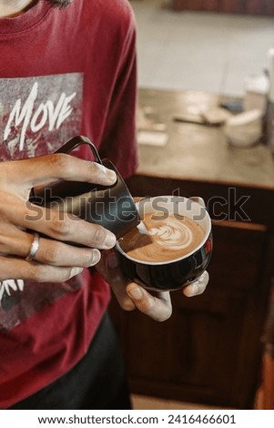 A person starts off their day by multitasking, holding a cup of coffee and a cell phone.