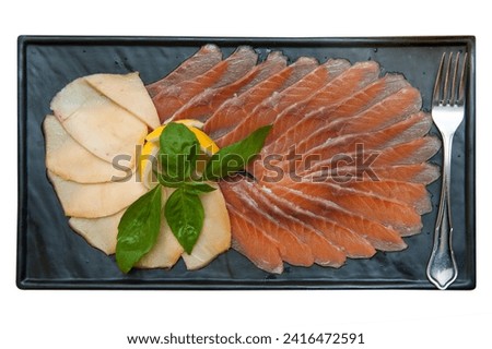 Fish platter with salmon slice and halibut, decorated with lemon and basil on a rectangular marble plate isolated on white background.