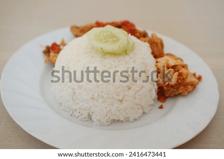 Rice with fried chicken and cucumber on white dish, stock photo