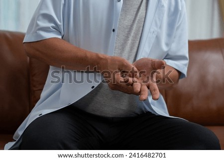 Elderly Asian male patients suffer from numbing pain in hands from rheumatoid arthritis. Senior men massage his hand with wrist pain. Concept of joint pain, rheumatoid arthritis, and hand problems.