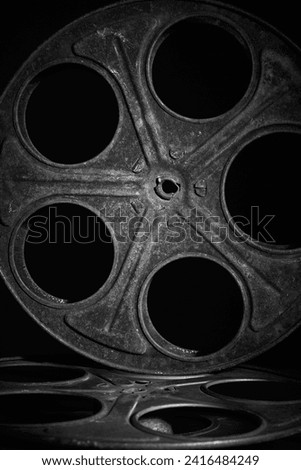 Old weathered rusty film spool or reel over a black background. Ancient movies background. Black and white photography.