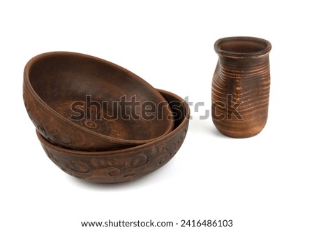 Two deep handmade clay plates and a close-up drink bowl. Isolated objects on a white background. Side view. Kitchen utensils, dishes for food Royalty-Free Stock Photo #2416486103