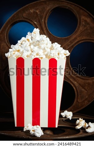 Popcorn bucket with an ancient rusty film reel or bobbin on the background.