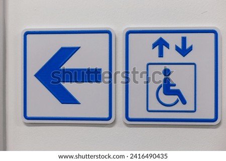 A blue arrow and elevator access signs disabled person on the wall