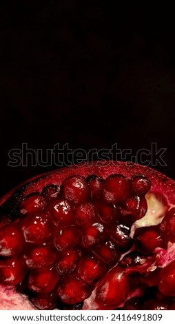 A pomegranate is a sweet, tart fruit with thick, red skin. While the skin is not edible, it holds hundreds of juicy seeds that you can eat plain or sprinkle on salads, oatmeal, hummus, and other dish Royalty-Free Stock Photo #2416491809