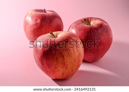 three red apples on a pink background 1