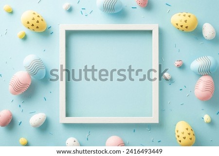 Playful holiday charm. Top view of a vacant picture frame, sugar sprinkles, and lively eggs against a pastel blue background. Perfect for personal messages or advertising