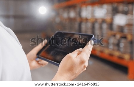 Factory worker with computer tablet inspecting kegs with beer in warehouse of modern brewery stock, blurred background. Royalty-Free Stock Photo #2416496815