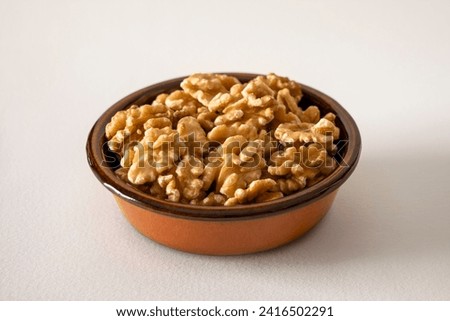Walnuts in a baked clay dish on white background