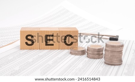 SEC text is written in wooden blocks on a table with numbers with coins on a white background