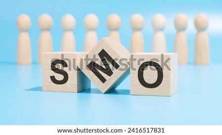 wooden blocks spell SMO, emphasizing the importance of optimizing social media. figures represent collaborative efforts. it conveys the need for effective strategies to enhance social media presence
