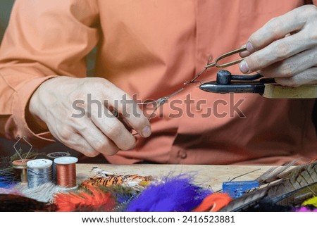 Tying a fly fishing fly. A set of various accessories and materials for tying fly fishing lures. Close-up. Royalty-Free Stock Photo #2416523881