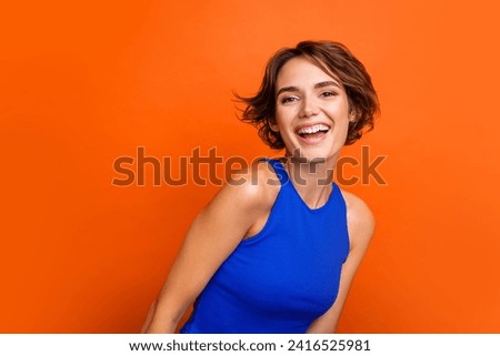 Photo of adorable excited girl dressed blue top smiling laughing empty space isolated orange color background