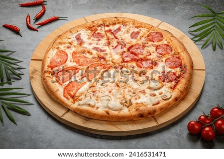 Juicy, delicious baked pizza with cheese, tomatoes, mushrooms and sausage on a wooden board. The composition is on a gray background with leaves and red pepper. View from above.