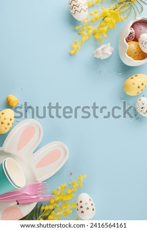 A kids' Easter extravaganza: egg-citement and joy unleashed. Top view vertical photo of bunny shaped plate, eggs, cups, cutlery, mimosa, sprinkles on light blue background with space for greeting text