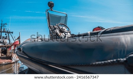 close-up view of a military inflatable boat on the dock with ship cranes in the background under clear blue skies