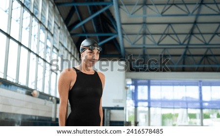 Professional female swimmer preparing and jumping off the starting block into the pool. Competitive swimmers workout concept.