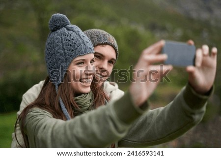 Couple, selfie and smile while hiking in nature, smartphone and capture moment in outdoors. People, happy and picture for memory and exploring wilderness, trekking and photograph for social media