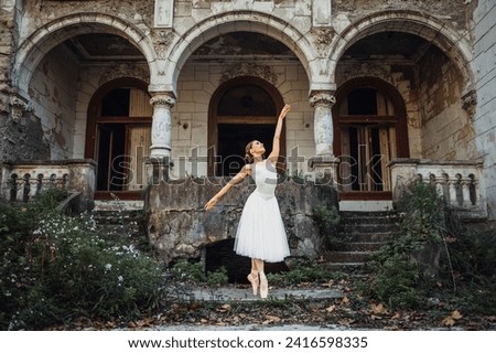 A gracious prima ballerina is performing dance and her art in ghosted and rustic exterior. An elegant diva is dancing and standing on her tiptoes at pointe in her tutu skirt in at abandoned place. Royalty-Free Stock Photo #2416598335