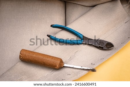 staple remover and upholstery pliers on a gray vinyl, flat layer. Royalty-Free Stock Photo #2416600491